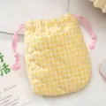 Gros plan sur la pochette matelassée jaune à carreaux avec cordon et motifs de cœurs. - Carreaux de coeur jaune matelassé