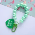 Close-up of mint green iridescent beads and a green heart-shaped FOR EVER tag. - Green