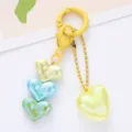 Close-up of iridescent acrylic heart pendants on a vibrant yellow metal keychain accessory - Yellow