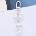 Detail showing the iridescent acrylic bear and bow on this cute white metal keychain - White