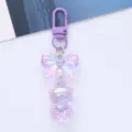 Close-up detail of iridescent acrylic bear keychain with purple bow and gradient finish - Purple