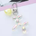 Macro detail of a trendy iridescent balloon dog keychain with yellow heart charm. - Yellow