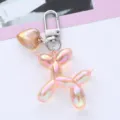 Close-up detail of a pink iridescent balloon dog keychain featuring a gold heart charm - Orange