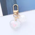 Close-up of a cute acrylic heart keychain with colorful clouds and iridescent bead. - White