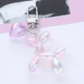 Close-up of iridescent pink balloon dog keychain with matching heart charm accessory. - Purple