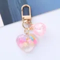 Close-up of a cute acrylic heart keychain with colorful snowflake charms for bag decor. - Pink