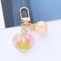 Close-up of a colorful heart acrylic keychain with iridescent bead and gold clasp - Orange