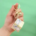 Close-up of cute cartoon rabbit cube keychain with golden bell and clasp detail - Yellow / 0.1