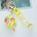 Detailed view of a yellow acrylic oil-filled lollipop keychain with a cute wish strap - Yellow