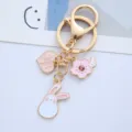 Close-up detail of pink rabbit and cherry blossom enamel charms on a golden metal keychain - Single Piece / Peach Long-eared Rabbit