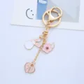Close-up detail of a girly gold keychain featuring pink rabbit, cherry blossom, and heart charms - Single Piece / Peach Heart Long-eared Rabbit