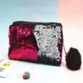 Detalle de lentejuelas reversibles en estuche de maquillaje con pompón - Rojo Rosa + Plata