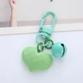 Close-up of a faceted heart charm and candy-colored bell on a mint green keychain - Single Piece / Green