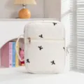 Detailansicht der gesteppten Buchhülle in Creme mit schwarzer Schleifenstickerei - Handgeführte Buchhülle / Beige Gestickte Schwarze Schleife