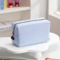 Detailweergave van de lichtblauwe wafeltextuur en metalen rits van een grote toilettas - Lichtblauw