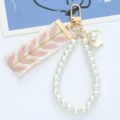 Macro view of elegant pearl bead loop keychain featuring pink leaf embroidered ribbon charm - Pink