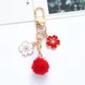 Close-up view of a Japanese style cherry blossom keychain with a soft red pom pom charm - Red
