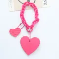 Detailansicht eines leuchtend pinken Herz-Schlüsselanhängers aus Acryl mit Logo-Prägung - Fuchsia