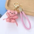 Close-up of pink knitted-texture resin bear keychain with braided wrist strap - Pink