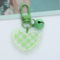 Close-up detail of the green checkerboard heart acrylic pendant with bell - Green Checkered Heart