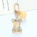 Macro detail of a colorful acrylic bear keychain with gradient crystal ball and gold clasp - Yellow