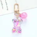 Close-up detail of a colorful gradient acrylic bear keychain with a gold metal clasp - Rose Red