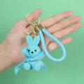 Detailed view of a light blue resin bunny keychain featuring a braided strap and bow - Blue