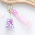Close-up of cute pink unicorn oil floating bottle keychain with a wish silicone strap - Unicorn / Purple
