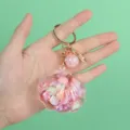 Close-up of a pink shell-shaped liquid-filled keychain with colorful sequins. - Shell Decoration / Pink Shell