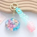Close-up of shell keychain with liquid quicksand and mint-pink gradient strap - Liquid Shell / Blue
