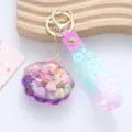 Macro detail of a creative oil-filled quicksand shell keychain with a purple blue strap. - Liquid Shell / Purple
