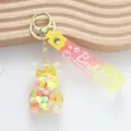 Close-up of a cute transparent bear keychain filled with colorful beads and pink strap - Jelly Bean Bear Style / Yellow