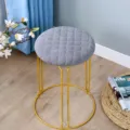 Moderner runder Hocker mit grauem Steppkissen und goldenen Metallbeinen für die Einrichtung. - Gesteppt / Grau