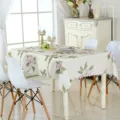 Vue détaillée d'une belle nappe rectangulaire à motif de magnolia rose sur une table à manger. - 90*90cm / Pivoine Beige