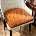 Vue détaillée du coussin de chaise en peluche marron, bulles texturées et base antidérapante. - Orange
