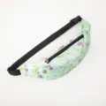 Close-up detail of a light green sports waist bag featuring pink flamingo and pineapple prints. - Light Green Flamingo