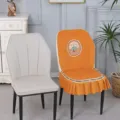 Detailed close-up of the quilted elastic dining chair cover featuring cute flower embroidery and skirt. - Curved Shell Chair Covers / Good Luck Style Orange