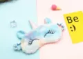 Close-up of soft plush unicorn sleep mask with colorful gradient and silver horn - Light Blue