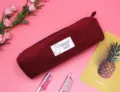 Détail de la texture en velours côtelé bordeaux et écusson alpaga sur la trousse. - Bordeaux