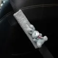 Detailed close-up of a cute gray plush rabbit car seat belt cover on a black leather seat - Blue Rabbit