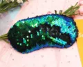 Close-up of reversible mermaid sequin eye mask with shimmering green and blue scales - Green + Matte Black