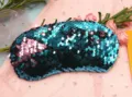 Detail macro view of reversible mermaid sequins in teal and pink on travel eye mask. - Blue + Pink