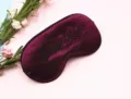 Nahaufnahme einer hochwertigen weinroten Schlafmaske aus Satin mit schwarzer Bestickung - Lila