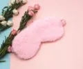Close-up macro view of soft plush pink rabbit fur eye mask on cozy floral background - Light Pink