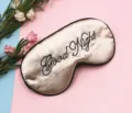 Detail of champagne satin sleep mask with elegant black Good Night embroidery for rest - Beige