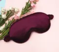 Macro detail view showing the smooth dark purple silk texture of this luxury sleep mask - Deep purple