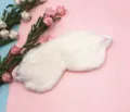 Close-up of white plush rabbit fur eye mask with soft satin elastic strap for sleeping. - White
