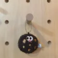 Detail view of cute plush chocolate chip cookie keychain on wooden pegboard - Charm / Dark Coffee (Sad Face)