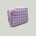 Detail showing the soft bubble grid texture of the lavender portable cosmetic bag. - Lavender