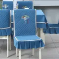 Close-up detail of blue quilted dining chair cover with embroidery and ruffle hem - Good Fortune Blue